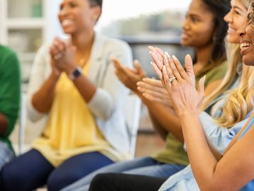Group of diverse people clapping and smiling.