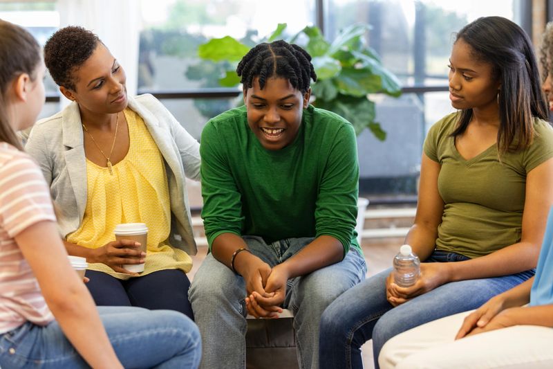 Multiracial group discusses personal challenges in a supportive, inclusive environment with a mental health professional guiding the conversation.