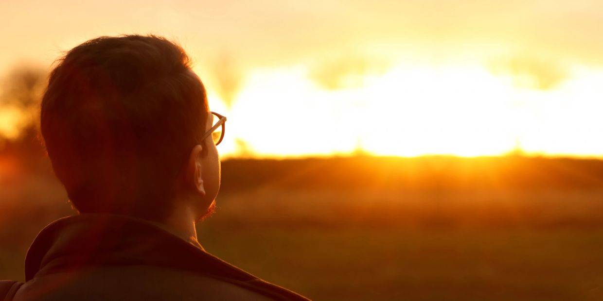 Man with glasses watching the sunset.