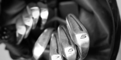 Close-up of golf clubs numbered 5, 6, and 7 in a bag.