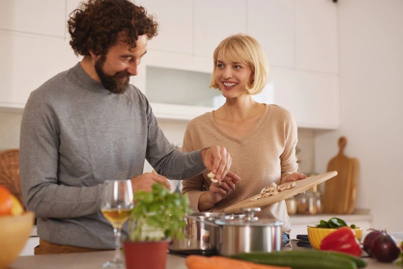 Cheerful couple preparing fresh vegetables and ingredients for a healthy meal in their home kitchen