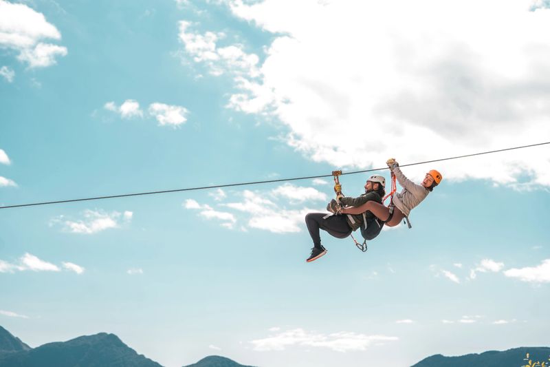 Young couple starting an elevated zip-line experience on a mountain expedition conquering heights and experiencing the rush of wind in an adrenaline-fueled outdoor escapade.