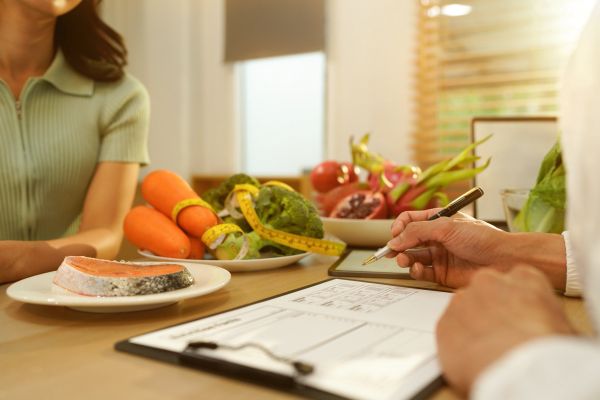 Person discussing nutrition with fresh vegetables and salmon on the table.