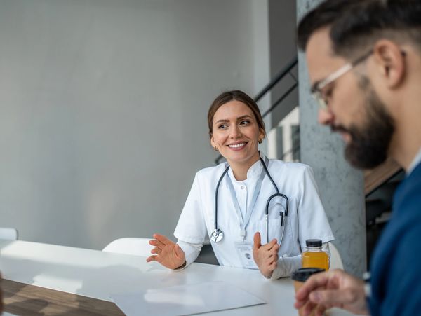 Female doctor in white coat smiling and talking during a meeting.