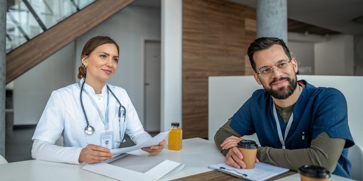 Two medical professionals in a meeting with coffee and documents.