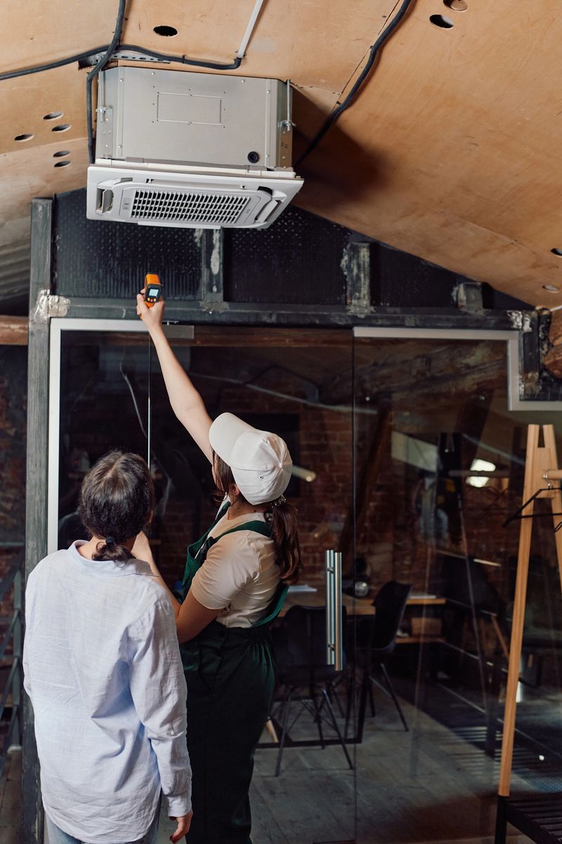 Women checking air conditioning units after installing indoors. Concept of indoor air conditioner inspection, cooling system test, technician at work, home comfort evaluation.