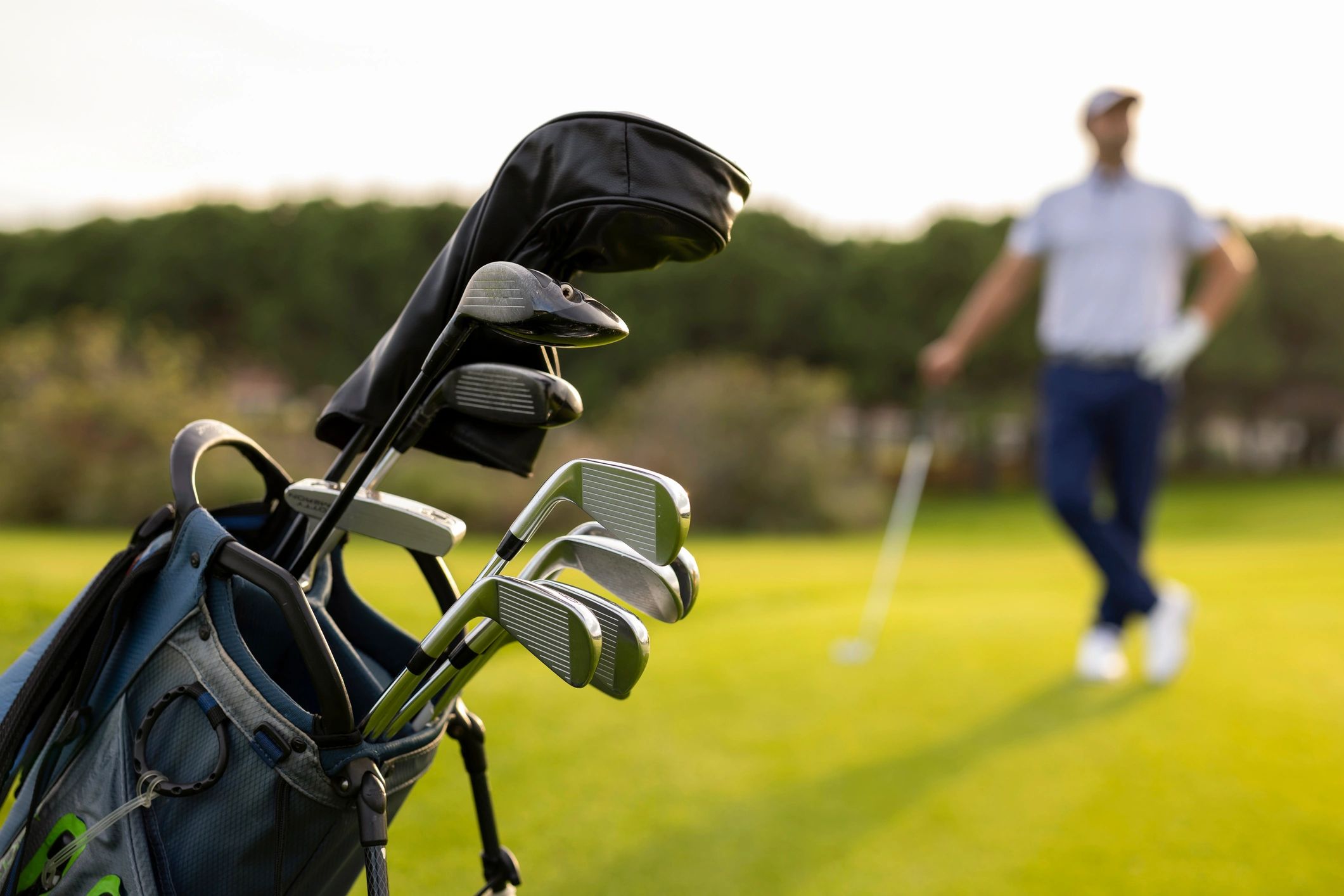 A set of golf clubs with the golfer at the golf course