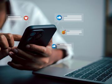 Person using a smartphone with social media reactions.