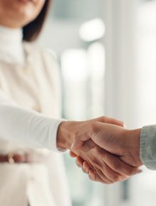 Two people shaking hands in a professional setting.
