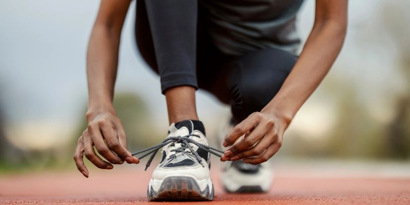 Person tying shoelaces on running shoes, preparing to run.
