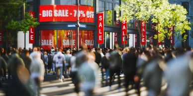 Crowded shopping street with big sale signs.