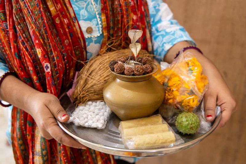 woman holding traditional pooja thali with flowers coconut and sacred items offerings at temple