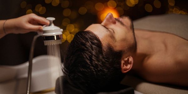 Man relaxing while getting a scalp massage with water spray.