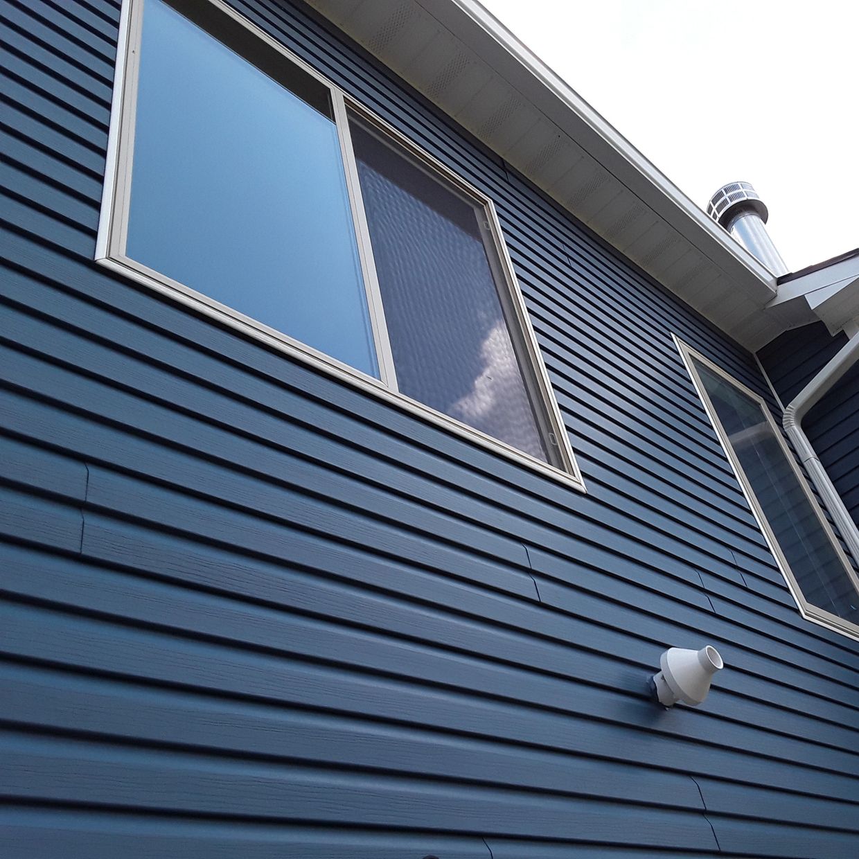 Blue house exterior with windows and chimney.