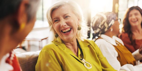 A joyful elderly woman laughing with friends.