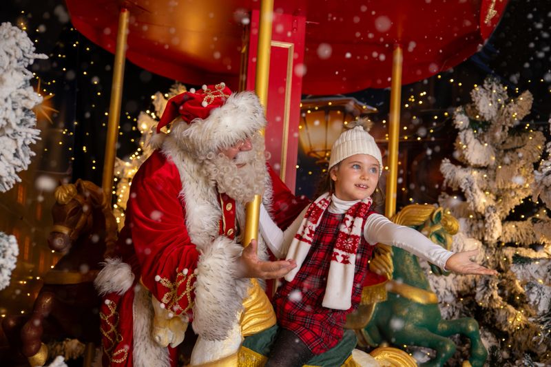 Santa Claus grandfather with his grandchild enjoy the winter Christmas advent on the carousel
