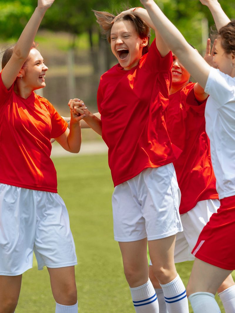 Female soccer players rejoice with passionate hug after winning on field. Concept of active lifestyle branding, success and motivation in sportswear imagery.