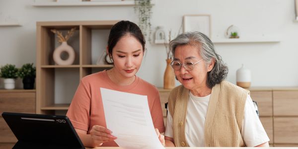 Young woman helping elderly woman review documents at home.
