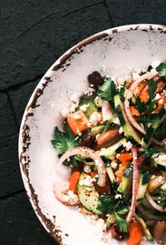Fresh vegetable salad with feta cheese on a rustic plate.