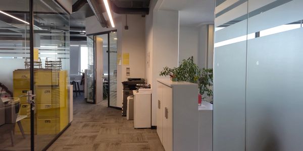 Modern office corridor with glass walls and storage boxes.