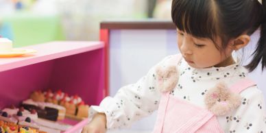 Young girl looking at desserts in a bakery.
