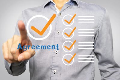 Person pointing at an agreement checklist with checkmarks.