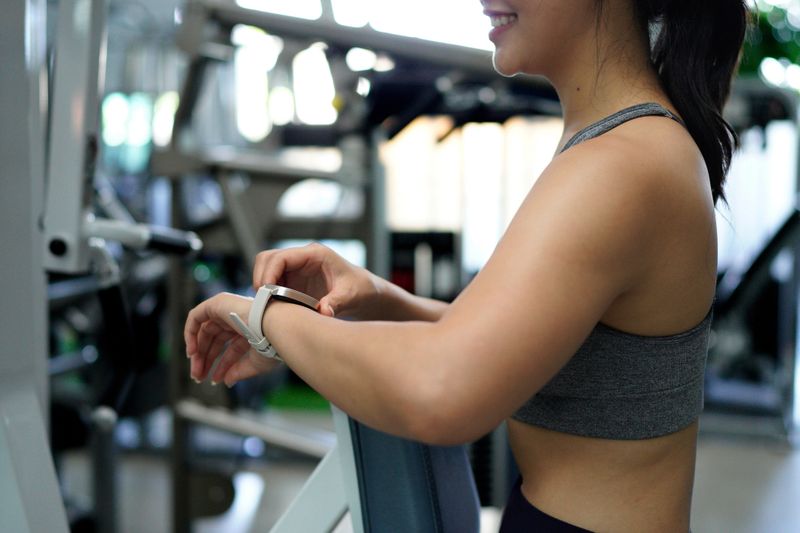 Lifestyle portrait of Asian young sporty woman watching and doing smart watch. Healthy lifestyle concept. Smiling Asian woman in sportswear looking and setup running program from smart watch.
