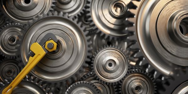 Close-up of metal gears with a yellow wrench adjusting one of them.