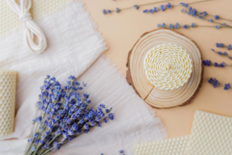 Beeswax candle and lavender bouquet on wood slice and fabric