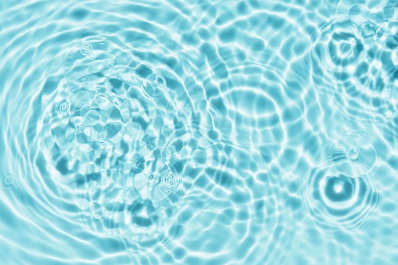 Water Background of Summer Pool and Waves Splash Abstract Pattern Texture on Swimming Poolside with Light,Shadow on Blue water, Sea Blue Circle Surface with Ripples,Splashes with Sunlight