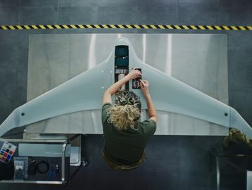 Person assembling a drone with large wings indoors.
