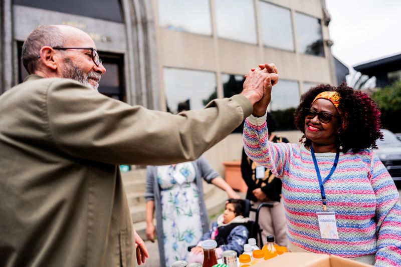 A dynamic moment of collaboration and enthusiasm captured between two volunteers during a community service project. Their raised hands and joyful expressions showcase the positive spirit of grassroots social engagement and collective effort.