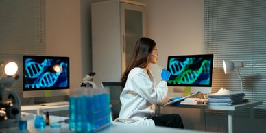 Scientist examining DNA sequences on computer screens in a laboratory.