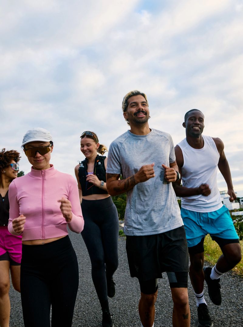 Diverse group of young adult friends running together outdoors, enjoying a morning workout