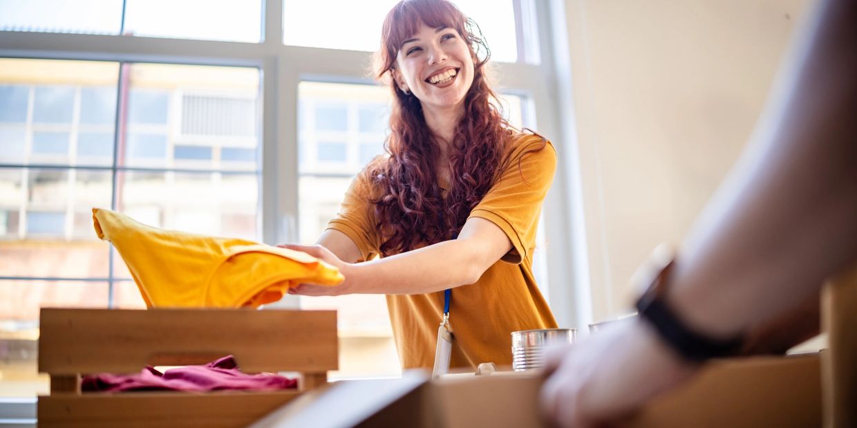 Smiling woman folding yellow clothes indoors.