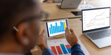 Person analyzing charts on tablet and laptop.