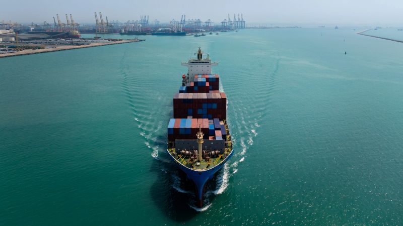 aerial view of large container ship sailing on deep sea, fully loaded with multi-colored containers, reflecting global business maritime transport cargo logistics,