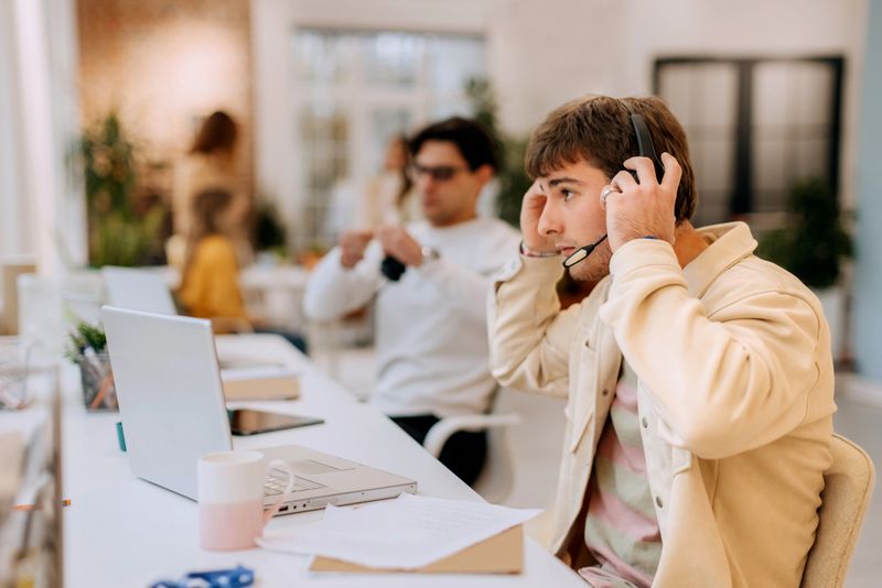 A businessman works as a customer support agent at a call center, wearing a headset while communicating with clients. Captures professional service, communication, and modern office environment.