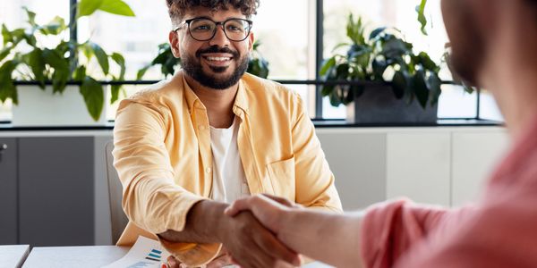 Two people shaking hands in a bright office setting.