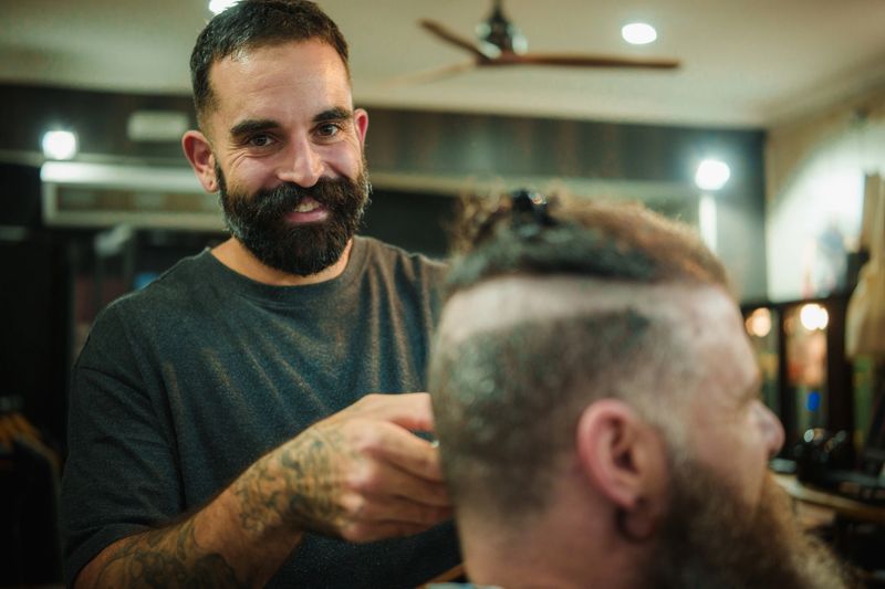 Smiling barber giving a customer a fresh haircut in a modern barbershop