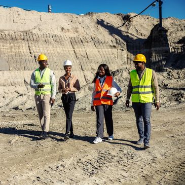Four construction professionals walking together at a worksite.