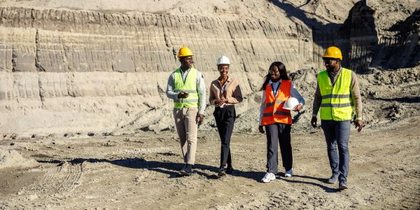 Four construction professionals walking together at a worksite.