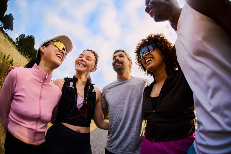 Laughing groups of young adults standing together outdoors during an early morning workout