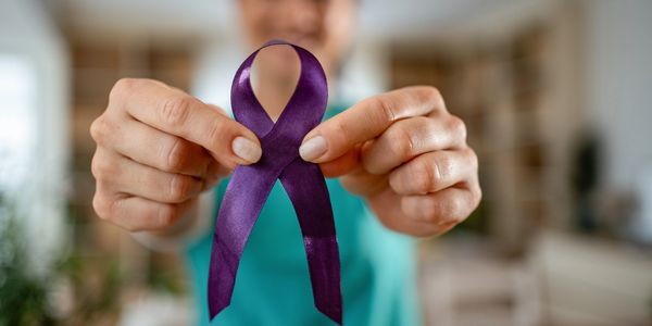 Person holding a purple awareness ribbon.
