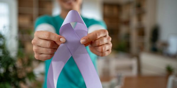 Person holding a purple awareness ribbon.