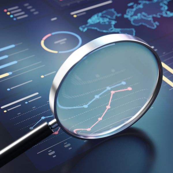 Magnifying glass examining data charts on a digital screen.