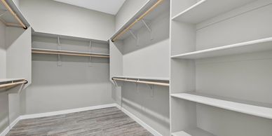 Empty walk-in closet with wooden shelves and hanging rods.