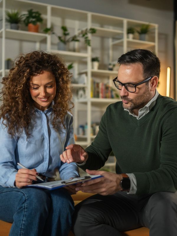 Two people discussing and reviewing documents together in a cozy room.