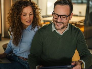 Two colleagues discussing work while looking at a tablet.