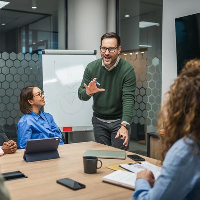 Man enthusiastically presenting ideas in a modern office meeting.